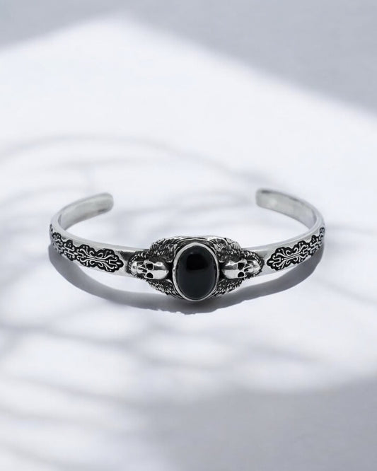 Close-up shot of a handcrafted 925 sterling silver skull bracelet featuring a polished black onyx gemstone. The oxidized silver finish enhances its gothic aesthetic, symbolizing strength, mystery, and individuality. Perfect for men who appreciate luxury handmade biker jewelry and bold accessories.