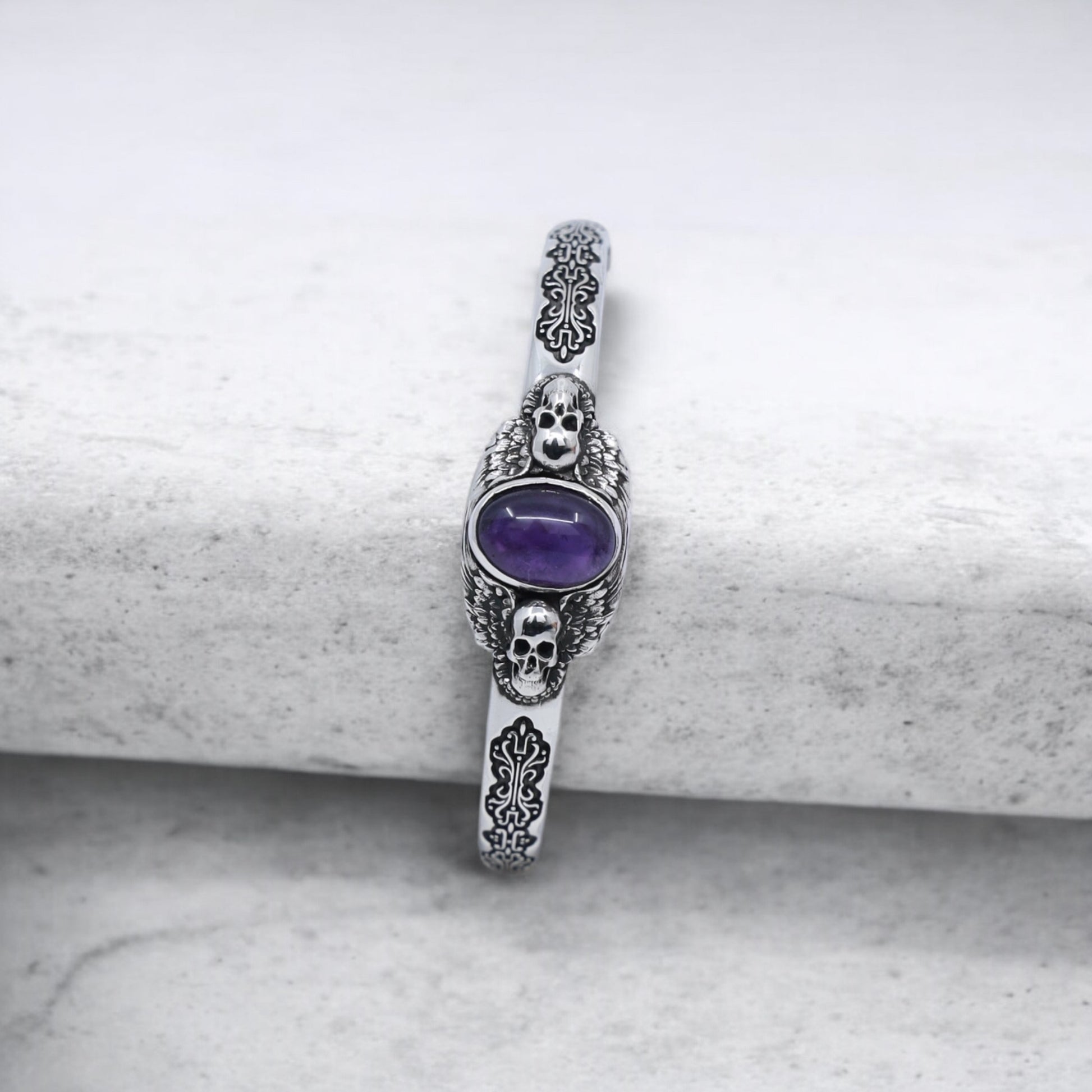 Detailed close-up of a skull-themed silver bracelet with a deep purple amethyst gemstone, made from 925 sterling silver. Its oxidized patterns and handmade design add timeless gothic charm to any men’s jewelry collection.