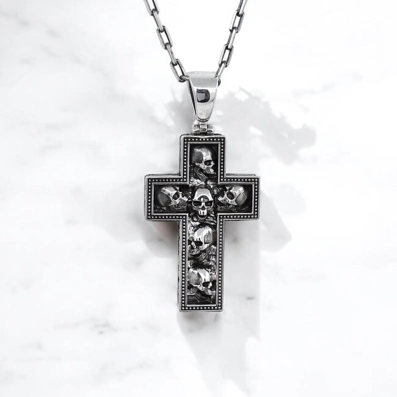 Men’s gothic skull cross necklace in sterling silver, featuring multiple skulls in a rugged cross design. Perfect for alternative fashion, biker lifestyle, and rock-inspired outfits. Durable, unique, and a great gift for bold personalities.
