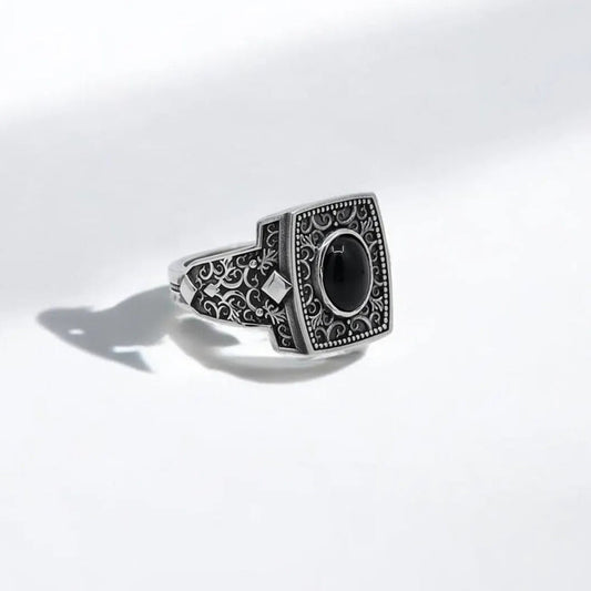 This handcrafted sterling silver onyx ring for men features a bold black gemstone set into an intricately engraved square bezel, surrounded by delicate gothic scrollwork that echoes ancient craftsmanship. Made from solid 925K silver, this mystical statement ring is a tribute to masculine energy, spiritual protection, and individual power. Ideal for those who appreciate deep symbolism in their accessories, it makes a perfect gift for a boyfriend, father, or husband with unique and elegant taste
