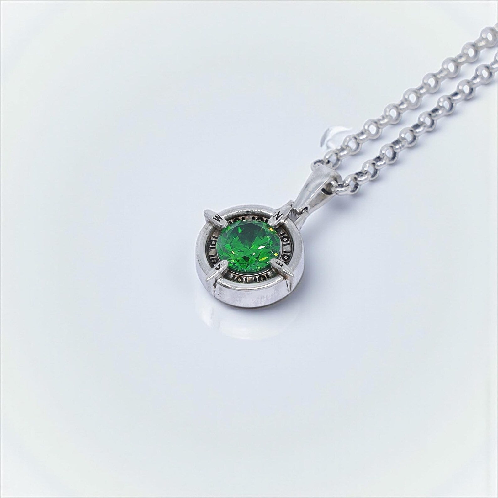Sterling silver handmade compass necklace with a dazzling emerald green gemstone, designed for travelers and adventurers. This symbolic nautical pendant makes a thoughtful jewelry gift for men and women, perfect for birthdays, anniversaries, or holiday celebrations. A meaningful artisan-crafted gemstone necklace with timeless appeal.
