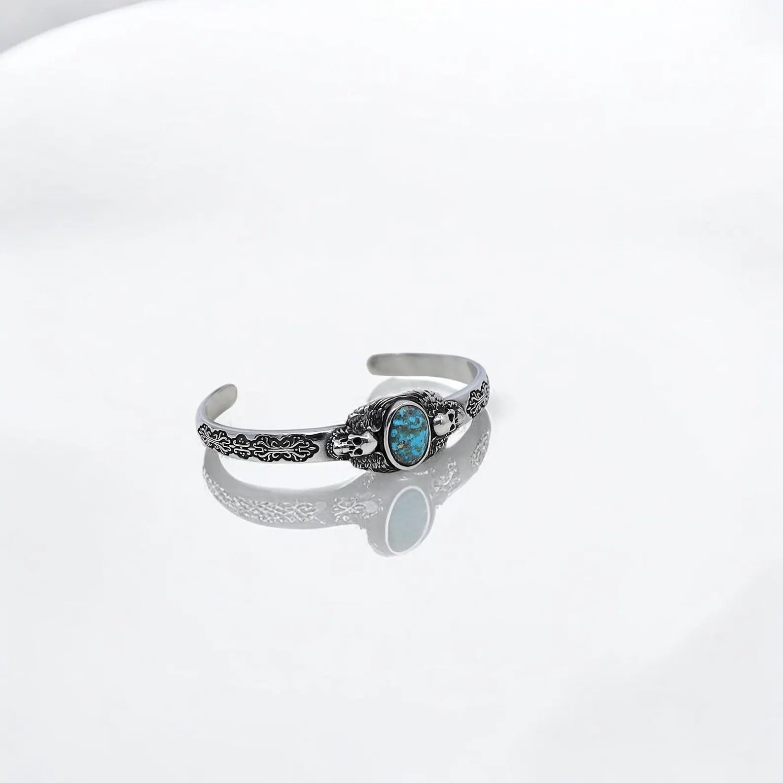 Close-up of the men’s turquoise stone silver bracelet, highlighting the intricately carved skull motif and the vibrant turquoise stone that adds a pop of color and spiritual depth. This handcrafted gothic bracelet combines Western flair, biker style, and timeless elegance, making it a unique and eye-catching piece that commands attention.