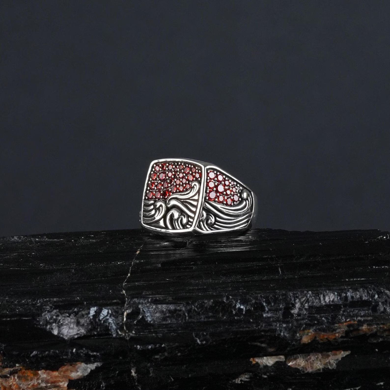 Detailed macro image highlighting the precision-carved wave patterns and the polished ruby gemstone centerpiece. Appeals to those searching for engraved sailor rings, personalized surfer gifts, or unique handcrafted jewelry pieces with character and charm.