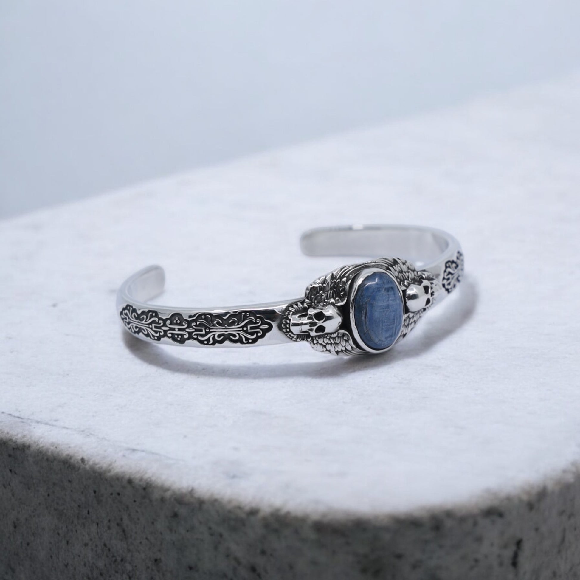 Minimal studio background featuring 925 silver skull bracelet with blue kyanite gemstone. A handcrafted gothic masterpiece that blends vintage charm with modern masculine elegance, made for men who appreciate quality artisan silver jewelry.