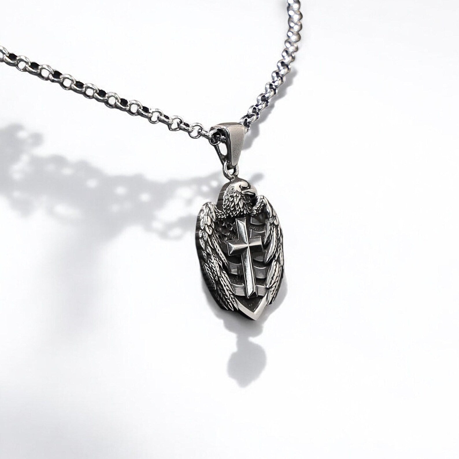 An intricately designed silver pendant for men, showcasing a detailed cross embraced by a majestic eagle figure. Handcrafted from high-quality sterling silver, this necklace merges gothic aesthetics with American symbolism, perfect for expressing identity and personal beliefs.