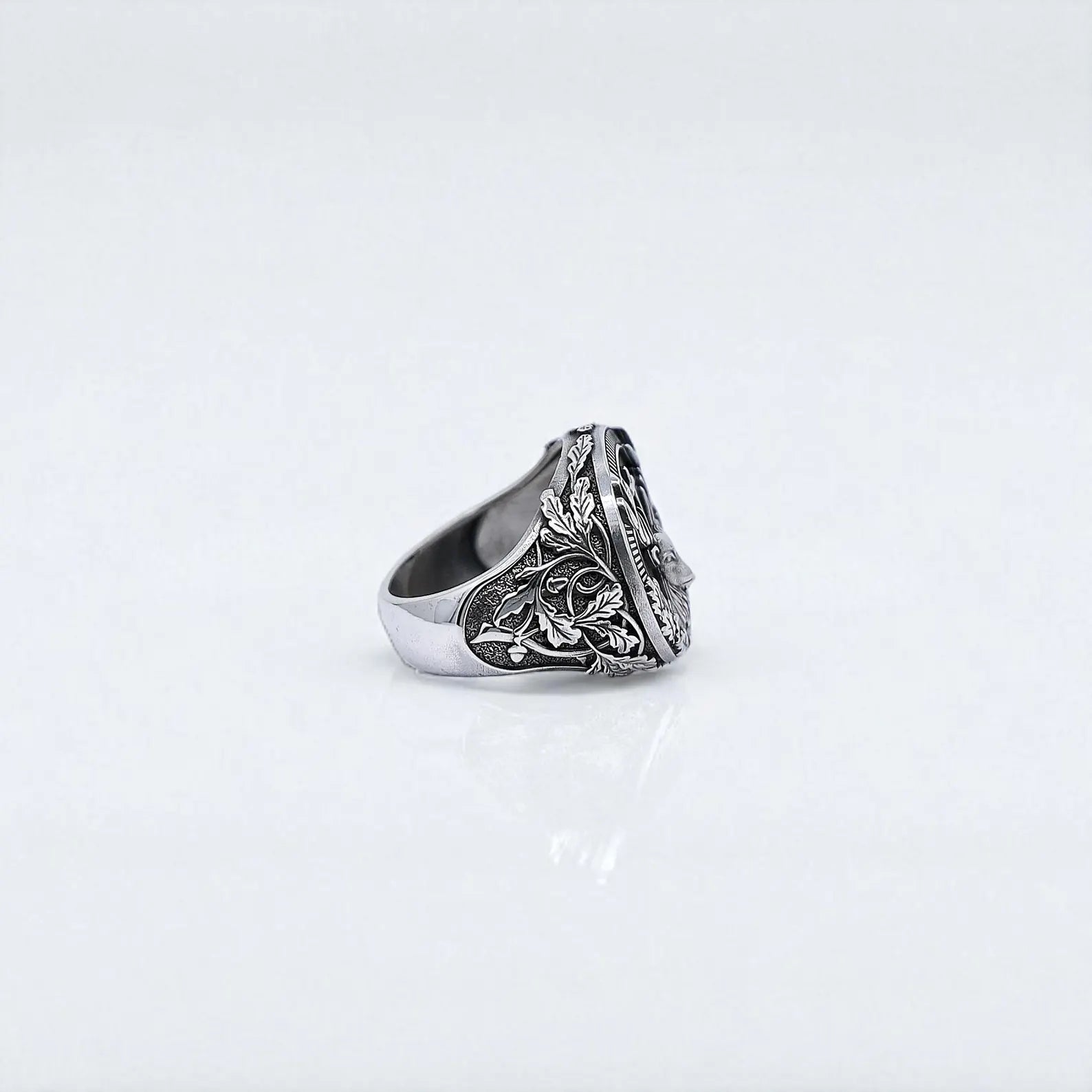 This bold mens silver ring showcases a deep-relief deer emblem with beautifully carved forest leaves and a radiant cross. The side detail captures the craftsmanship and artistic roots of woodland and medieval styles, ideal for personalized nature-themed accessories.