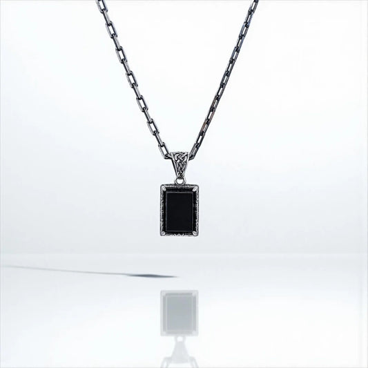 Handcrafted sterling silver necklace featuring a deep black onyx gemstone encased in a vintage-inspired pendant. The intricate engraving and polished finish make this elegant piece perfect for men who appreciate timeless, symbolic jewelry that can transition seamlessly from casual to formal wear.