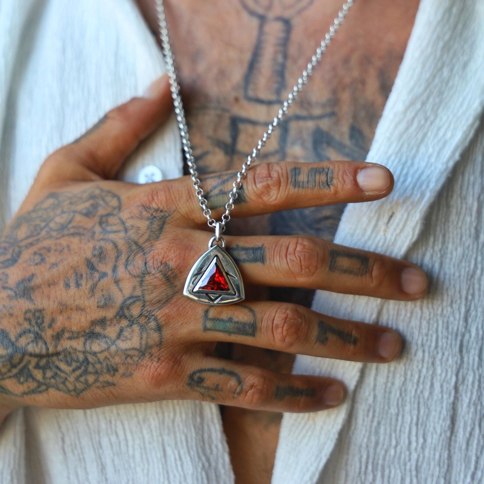 Artisan sterling silver pendant necklace featuring a deep red triangular stone, framed by engraved angular patterns that create a modern amulet look, perfect as a symbolic, meaningful gift for a loved one.