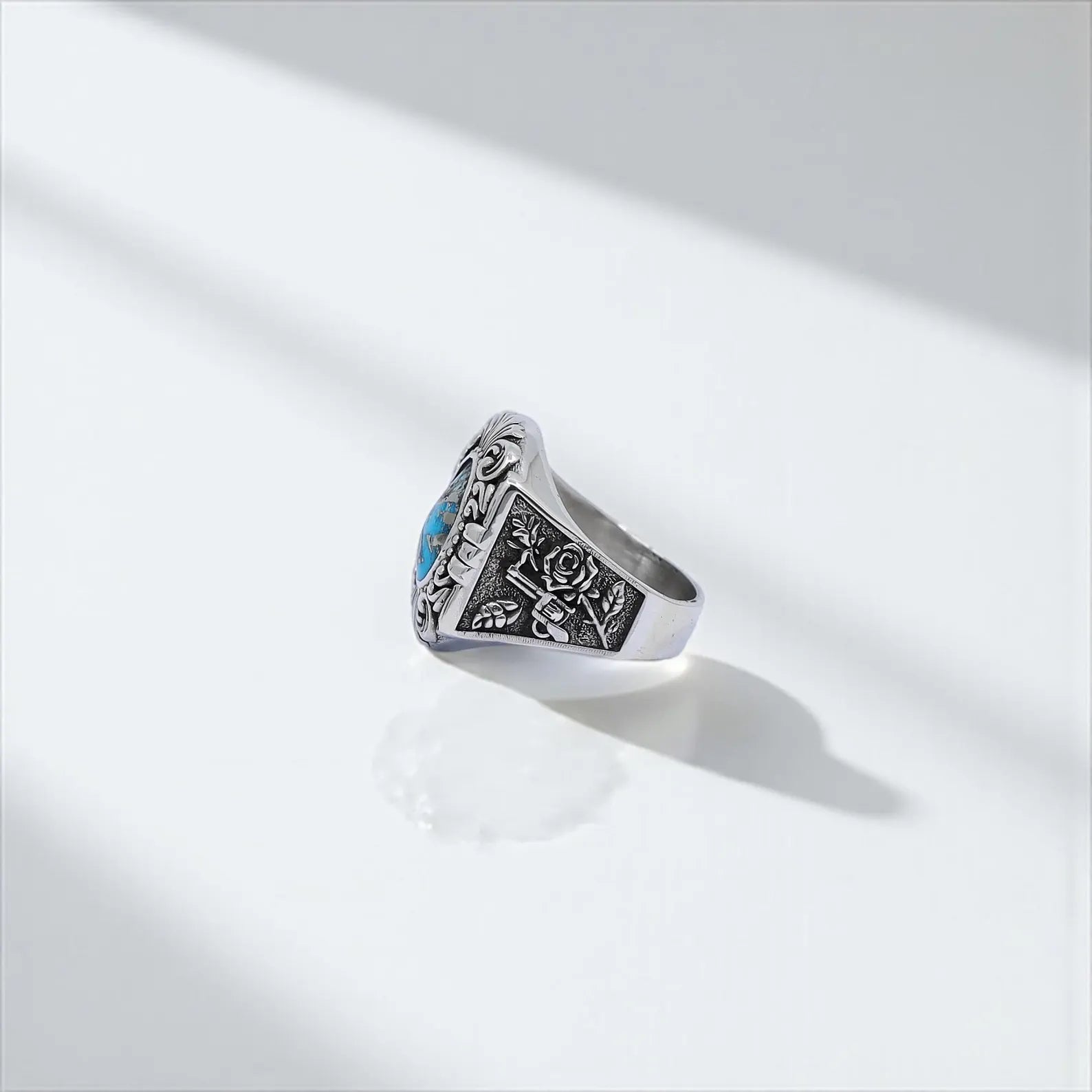 Elegant handmade sterling silver ring for men with deep blue turquoise centerpiece and symbolic rose and revolver side engravings – a perfect blend of boho and outlaw aesthetics.