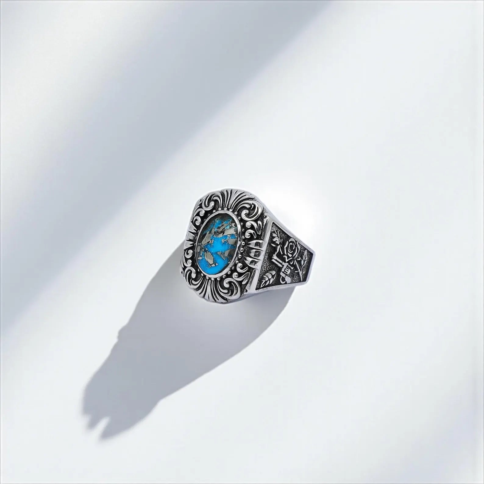 Unique western-style men's ring with turquoise gemstone and handcrafted guns and roses engravings, set in oxidized sterling silver – designed for men who embrace bold, meaningful jewelry.