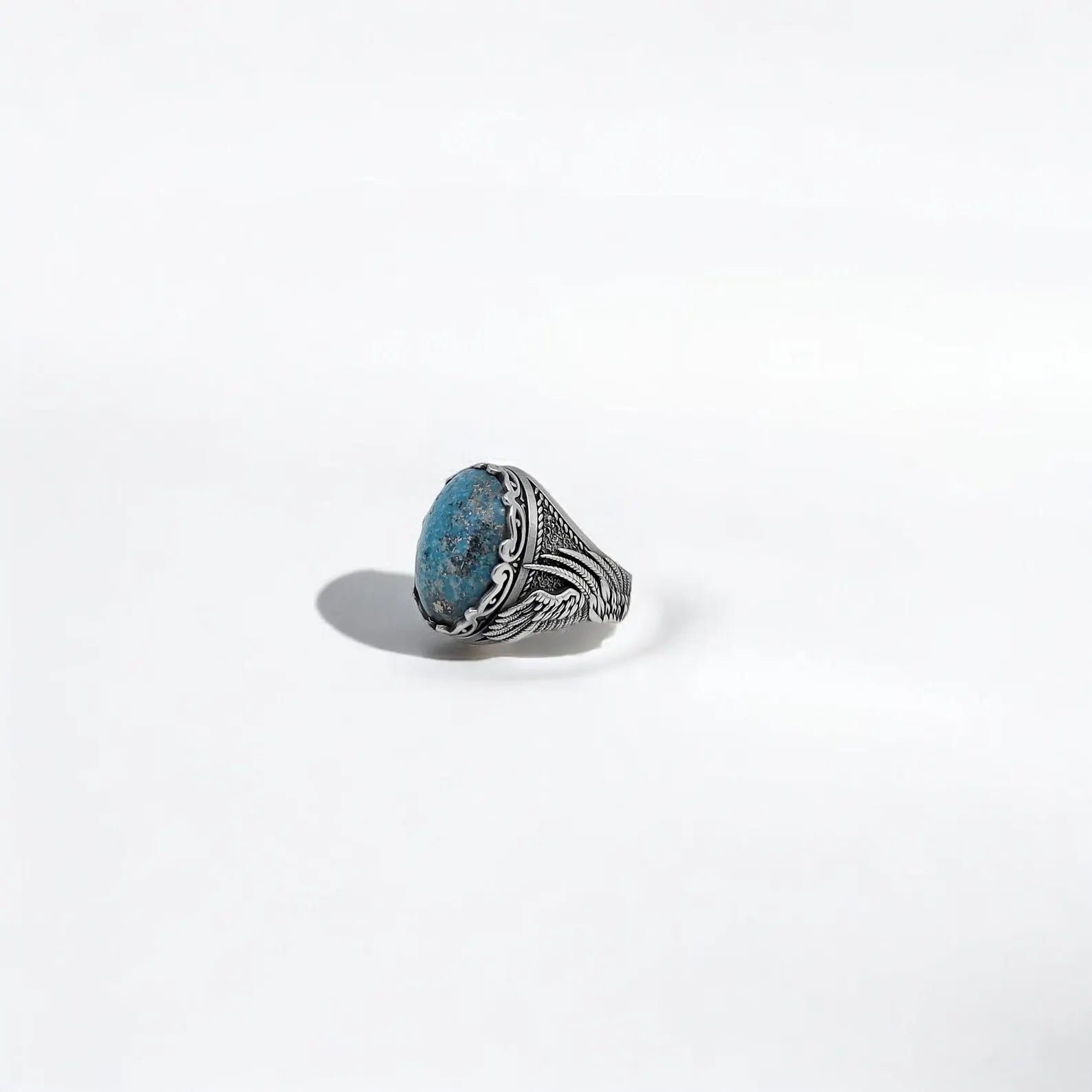 A striking 925K sterling silver ring featuring a richly textured natural turquoise stone and sculpted wings flowing down the sides. This gothic tribal ring embodies the spirit of the open road and the energy of the Earth. Whether worn as a talisman, a personal style statement, or a heartfelt gift, it reflects authenticity, courage, and handcrafted excellence. Ideal for anniversaries, birthdays, or commemorating a personal journey.