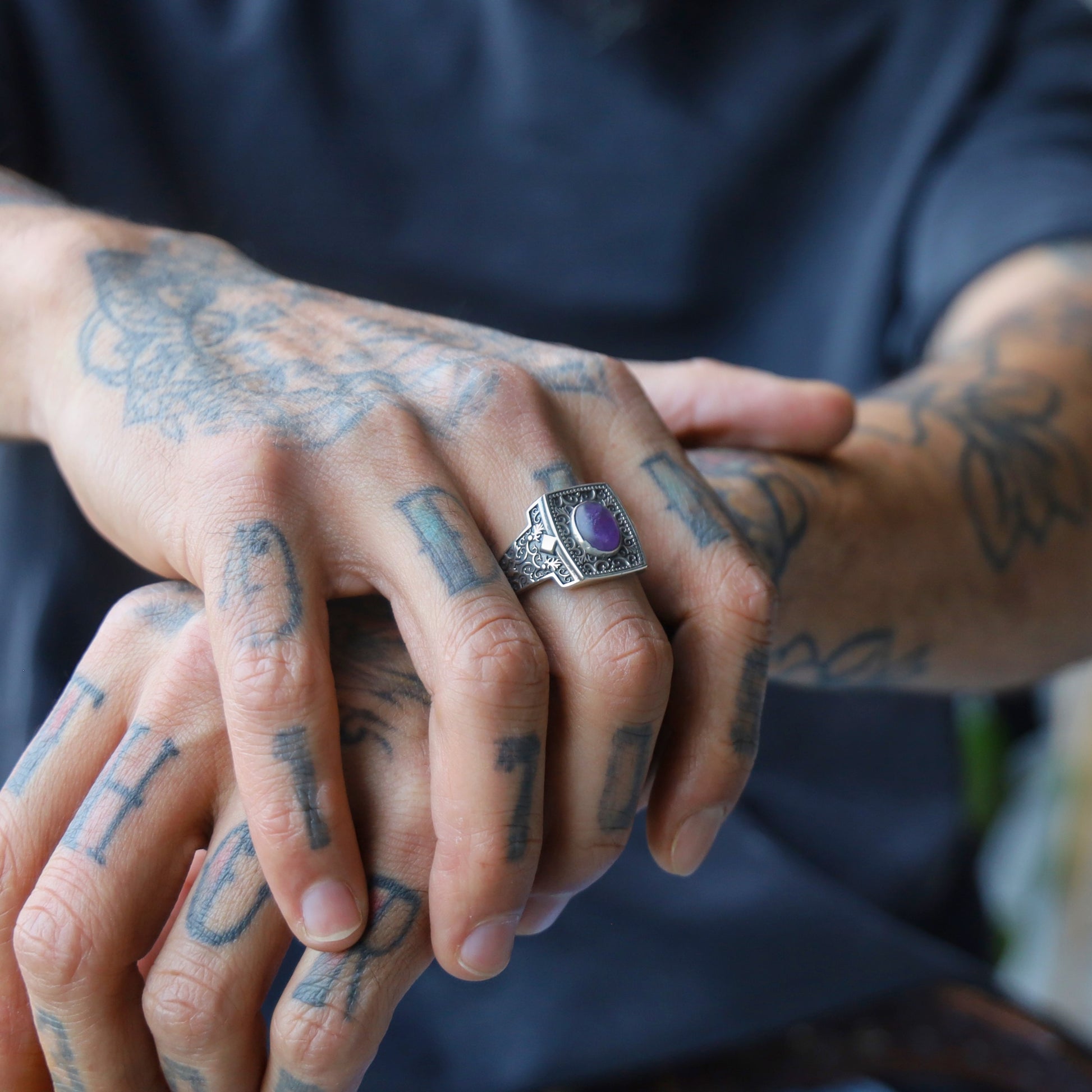 This engraved sterling silver ring showcases a vibrant amethyst gemstone at its center, symbolizing balance, clarity, and protection. The intricate patterns along the wide band evoke historical craftsmanship with a modern twist. Designed for confident men who prefer meaningful, expressive jewelry, this ring is an excellent choice for anniversaries, birthdays, or spiritual milestones.