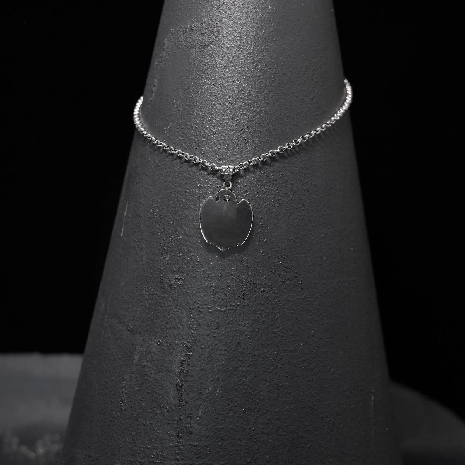 An angled close-up of the handcrafted Sterling Silver American Eagle Cross Pendant, capturing the fierce elegance of the spread-wing eagle wrapped around a detailed gothic cross. Symbolizing freedom, faith, and fearlessness, this men’s patriotic necklace is designed for those who proudly wear their beliefs. With its oxidized silver texture and precise detailing, this pendant is a powerful fusion of American heritage and gothic artistry