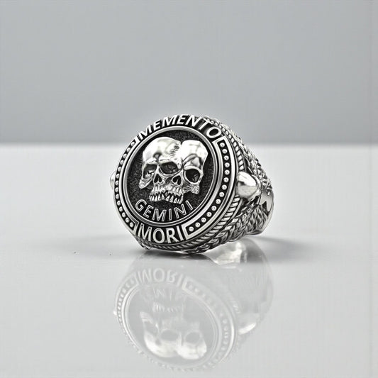 Handcrafted 925 sterling silver Gemini Skull Ring featuring an intricate twin-skull Memento Mori design, symbolizing duality, transformation, and zodiac energy, with deeply oxidized details and premium gothic craftsmanship for men who appreciate bold and meaningful jewelry.