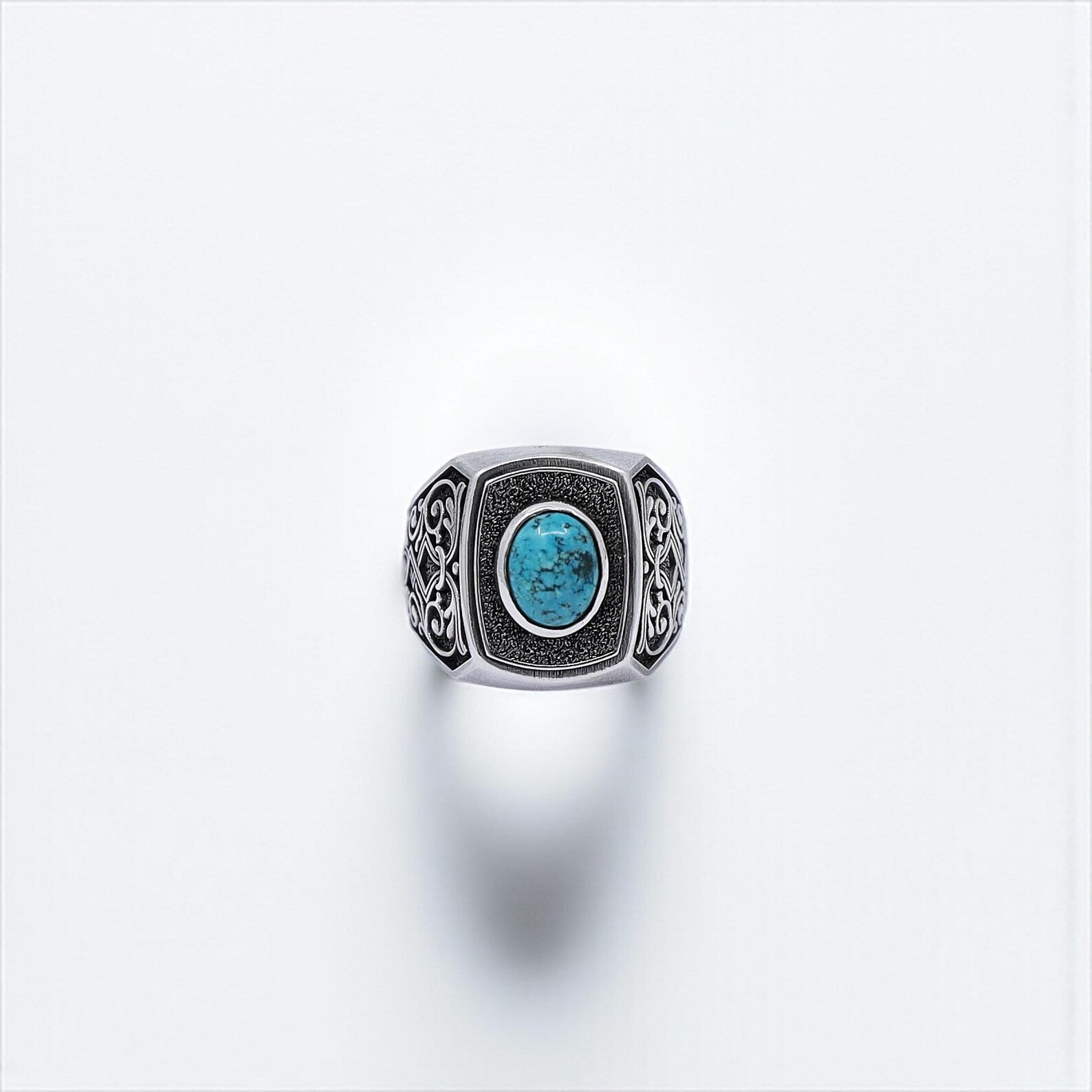 A high-quality silver ring for men with a vivid turquoise gemstone centerpiece, framed by finely detailed ethnic engravings — capturing the essence of tribal craftsmanship and rugged masculinity.