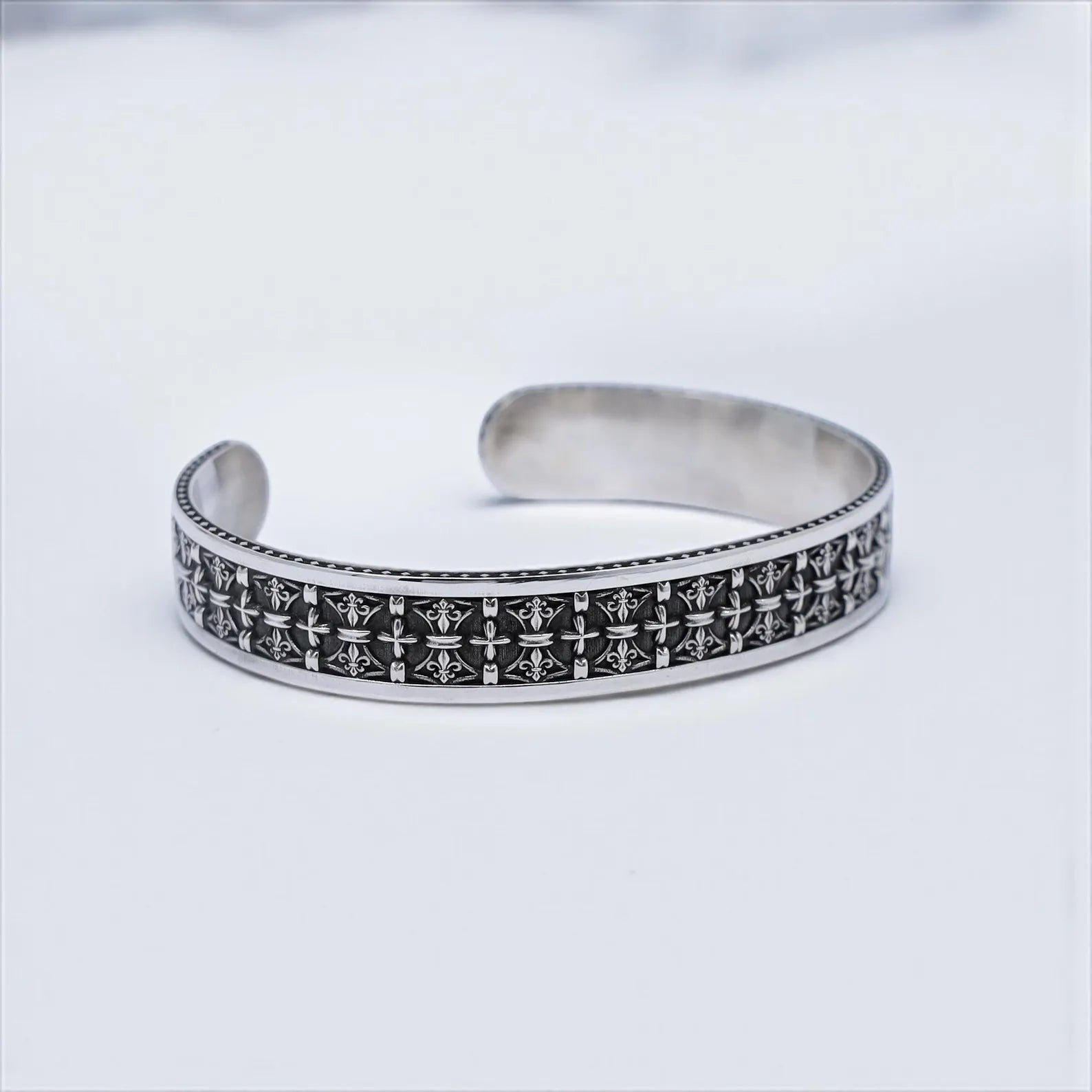 Close-up image of a masculine sterling silver bracelet with gothic-style cross motifs etched across its surface. A modern twist on medieval Christian symbolism, this cuff bracelet is hand-finished and made to impress. A versatile piece that complements both casual and formal looks while carrying spiritual depth.