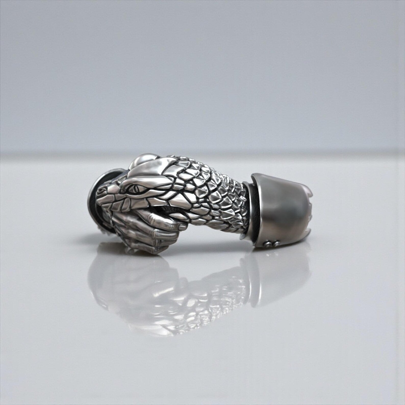 Men’s gothic snake and hand ring in solid 925 sterling silver, inspired by secret society symbolism, photographed to highlight its bold design, thick band and powerful masculine character