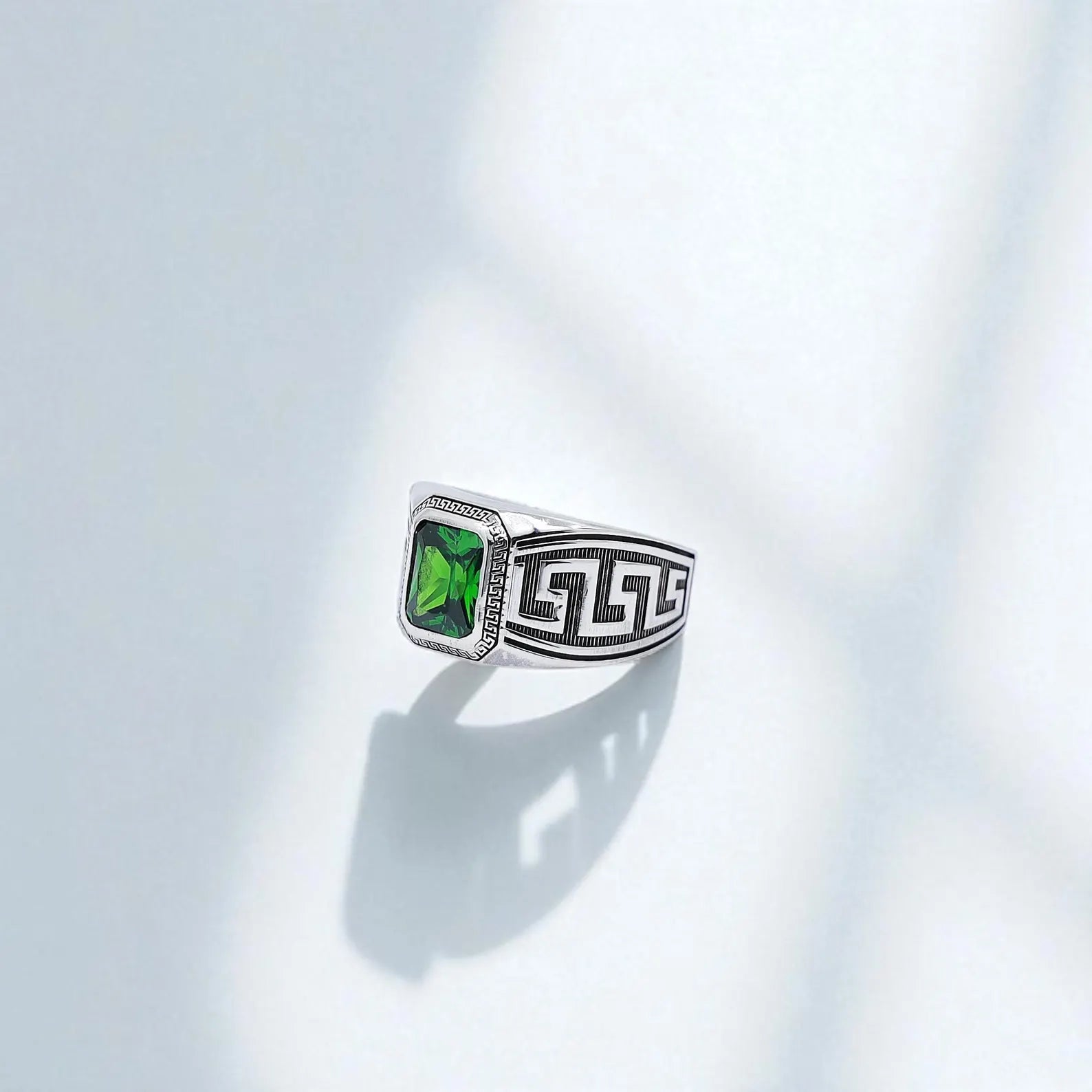 Side profile image of a sterling silver Greek key ring with a square-cut green gemstone centerpiece and deep engraved meander patterns. A meaningful and stylish choice for weddings, anniversaries, or daily wear by lovers of fine artisan jewelry.