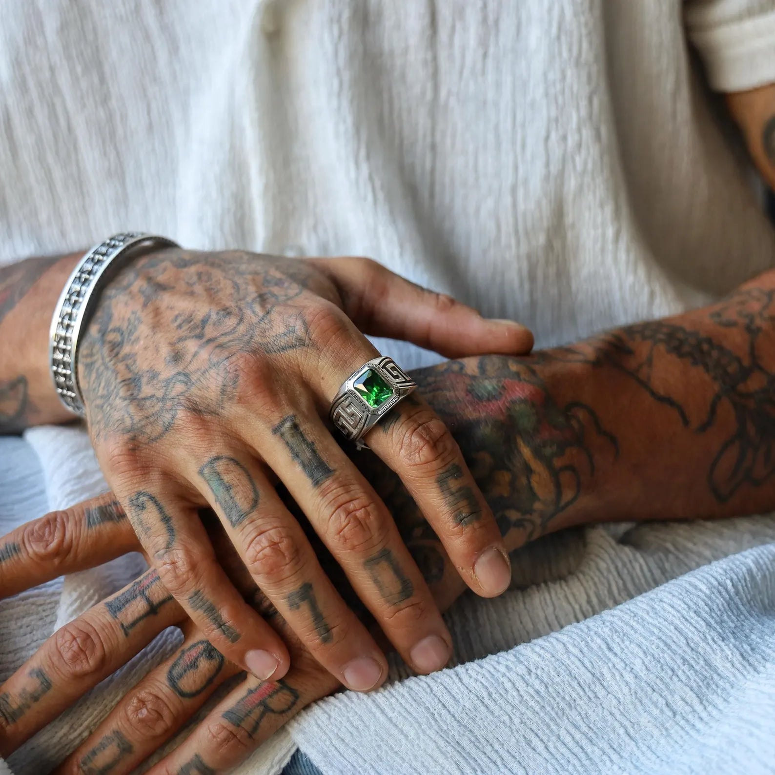 Mens statement ring made of solid sterling silver with traditional Greek key engravings and a bold emerald green stone in a classic cut, designed to capture strength, heritage, and luxury in one powerful accessory.