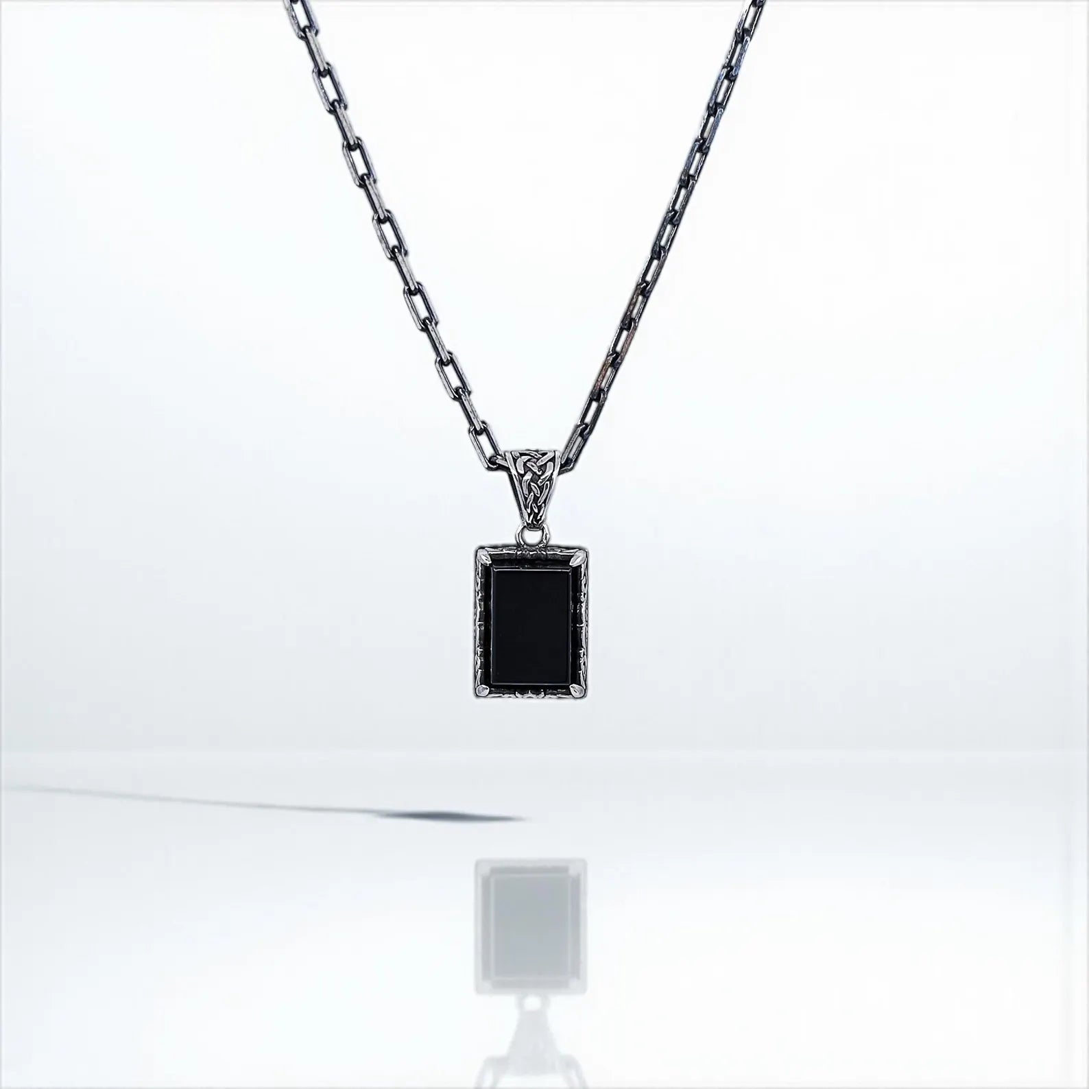 Handcrafted sterling silver necklace featuring a deep black onyx gemstone encased in a vintage-inspired pendant. The intricate engraving and polished finish make this elegant piece perfect for men who appreciate timeless, symbolic jewelry that can transition seamlessly from casual to formal wear.