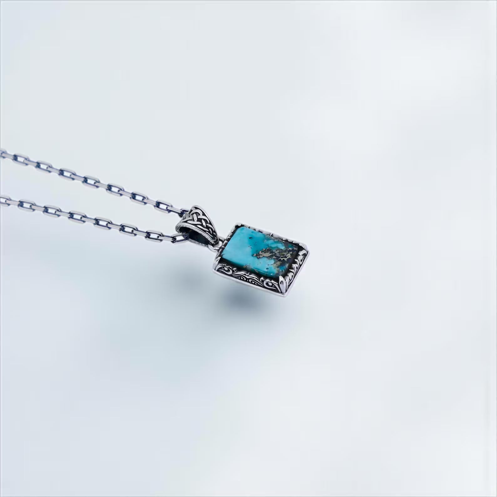 Detailed photo of a turquoise crystal pendant necklace with handcrafted ethnic motifs in sterling silver, combining fantasy elegance and rustic style – the perfect birthstone gift for him, father, or graduate.