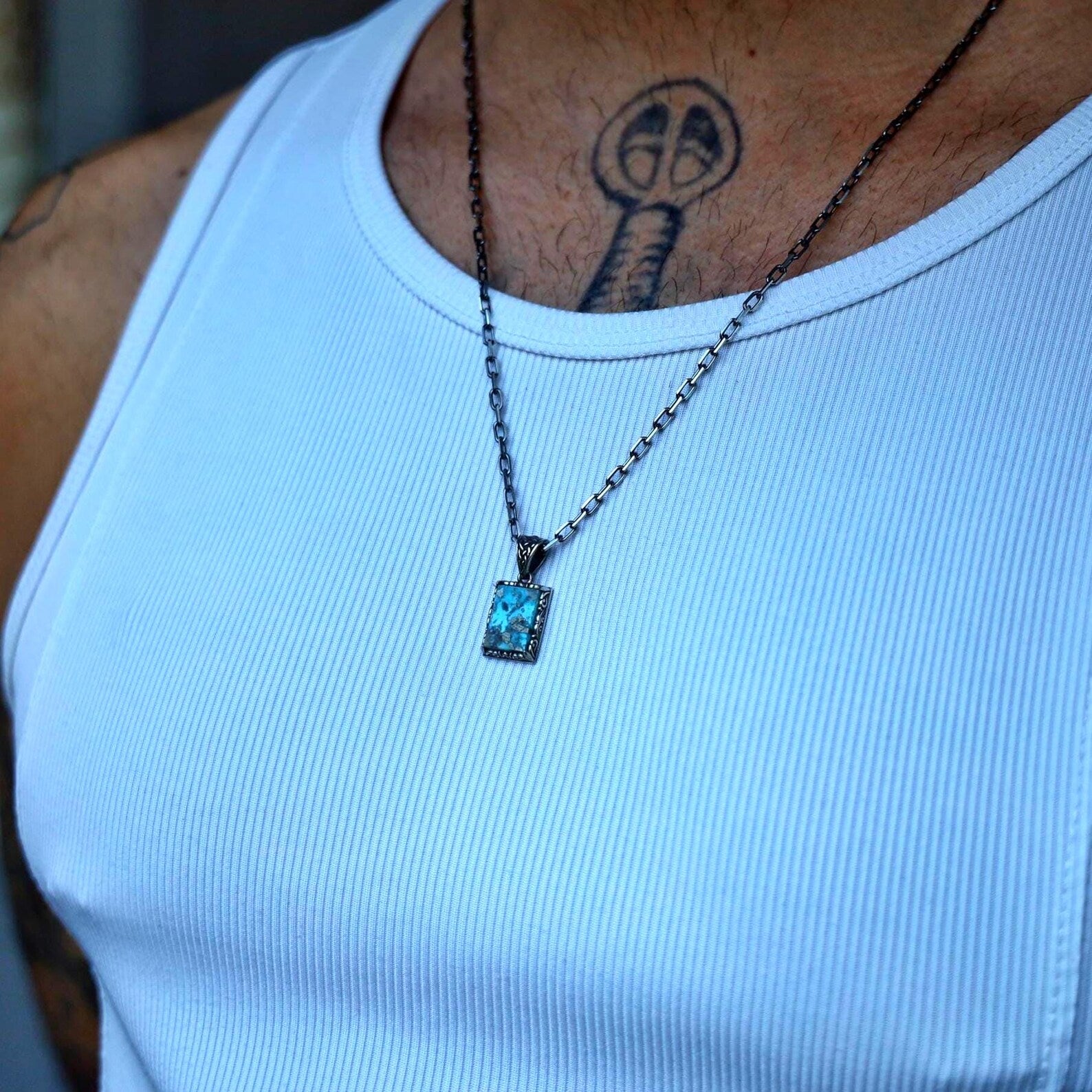 May include: A silver chain necklace with a small, rectangular pendant featuring a turquoise stone.