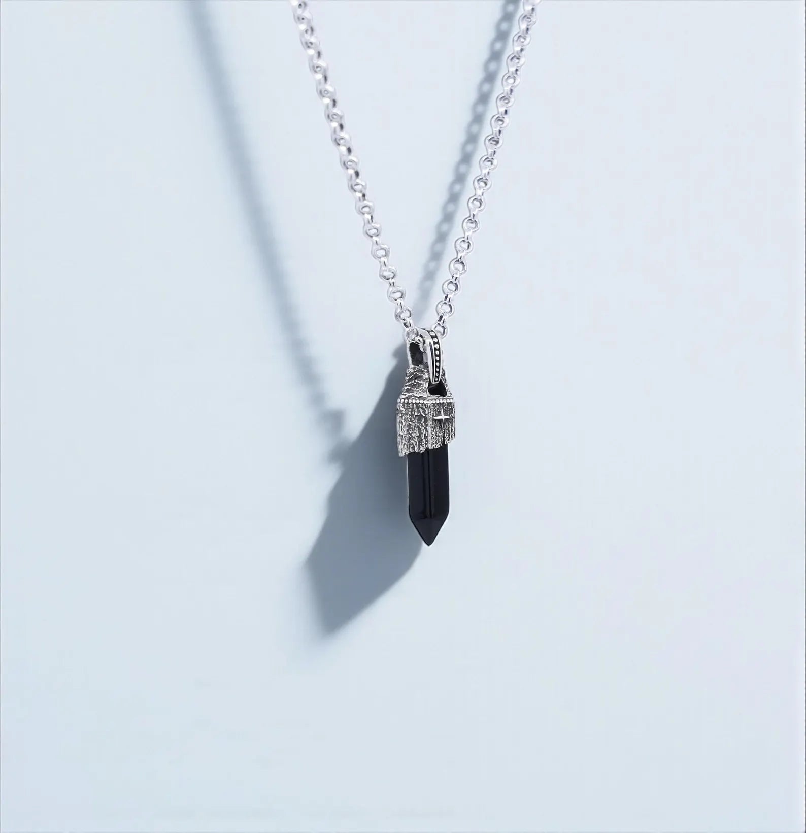 A high-quality spiritual obsidian necklace for men showcasing a natural black stone carved into a pointed pendant, wrapped in handcrafted 925 sterling silver with a compass emblem, combining vintage charm and protective energy.