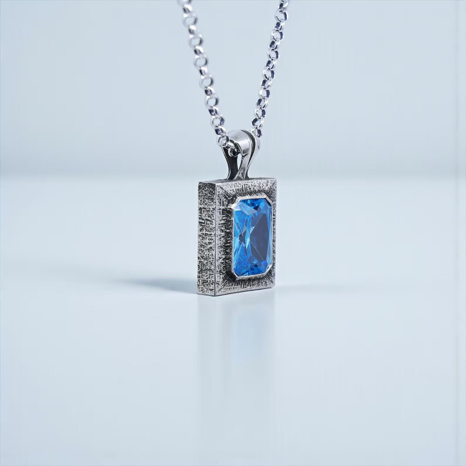 Luxury emerald cut blue topaz pendant necklace made from high-quality 925 sterling silver, showcasing a brilliant emerald-shaped blue topaz known for its calming and uplifting energy. Unisex handcrafted statement jewelry perfect for gifting on special occasions such as birthdays, anniversaries, or holiday celebrations.