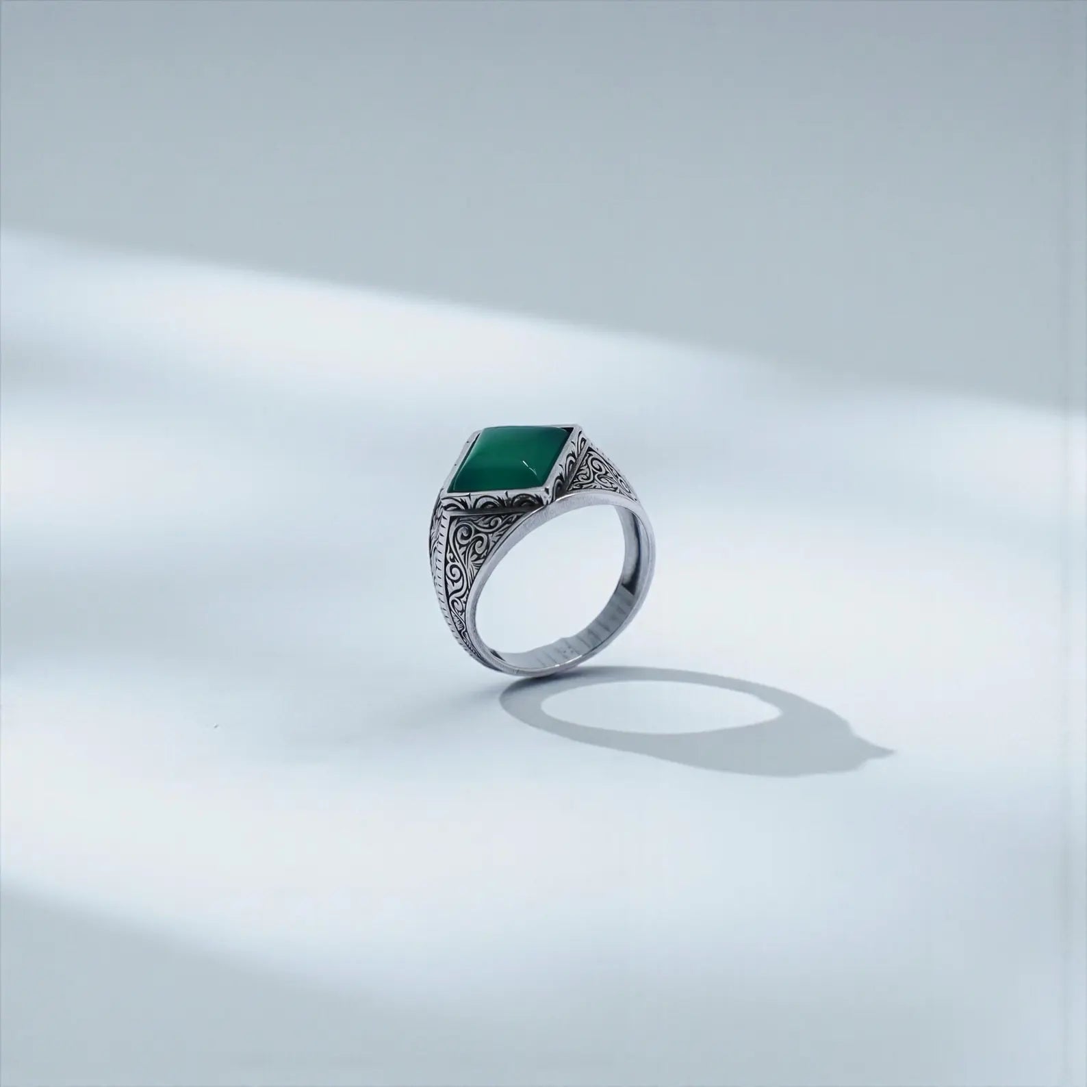 High-quality men’s statement ring with detailed baroque engravings in sterling silver and a powerful green onyx stone, symbolizing calmness, strength, and personal expression.