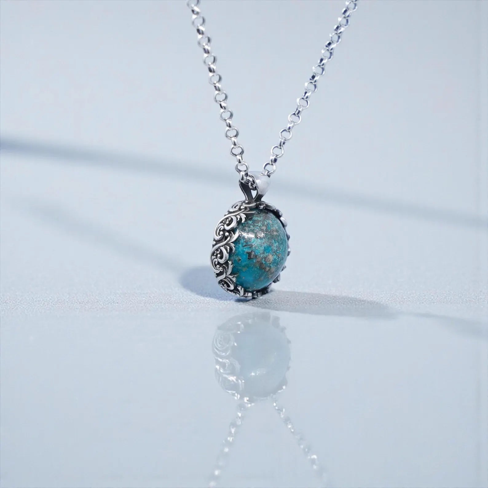 Elegant handcrafted turquoise stone pendant necklace designed for men, featuring a 20mm natural turquoise gemstone with vibrant blue and earthy matrix patterns, set securely in a vintage baroque-style sterling silver bezel with oxidized accents; a statement piece symbolizing grounding, wisdom, and good fortune, perfect for collectors of stylish artisan jewelry.