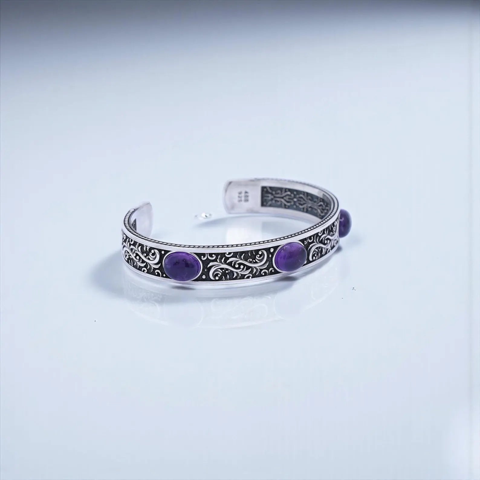Elegant vintage engraved sterling silver amethyst bracelet for men, showcasing three natural purple gemstones surrounded by ornate hand-carved patterns, offering a unique blend of timeless craftsmanship, biker style, and spiritual gemstone energy for daily wear or gifting.