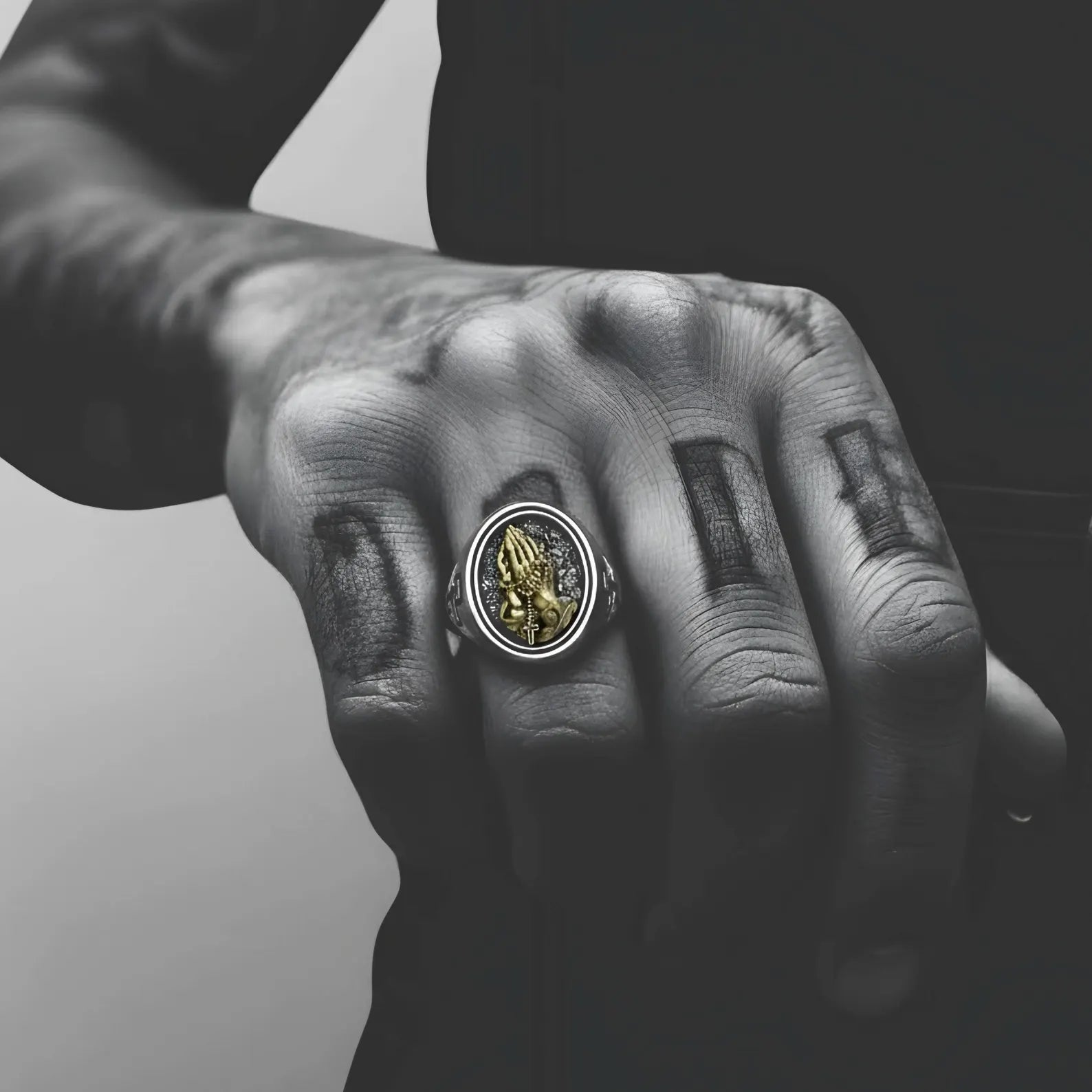 Men’s religious statement ring in oxidized sterling silver featuring praying hands, rosary beads, and a gold cross accent, representing devotion, humility, and inner strength