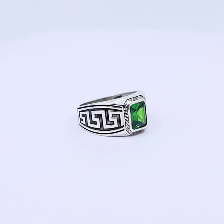 Close-up image of a handcrafted sterling silver Greek ornament ring for men, featuring an emerald-cut green gemstone in the center, surrounded by detailed Hellenic patterns that reflect ancient aesthetics and timeless elegance.